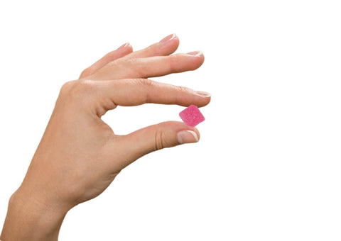 hand holding pink lemonade gummy on white background